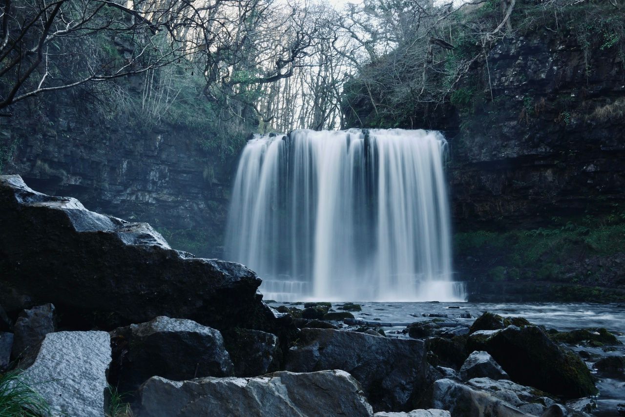 A waterfall called Sgwd-yr-Eira, The Falling of the Snow, makes a white curtain as it plunges into a pool below.